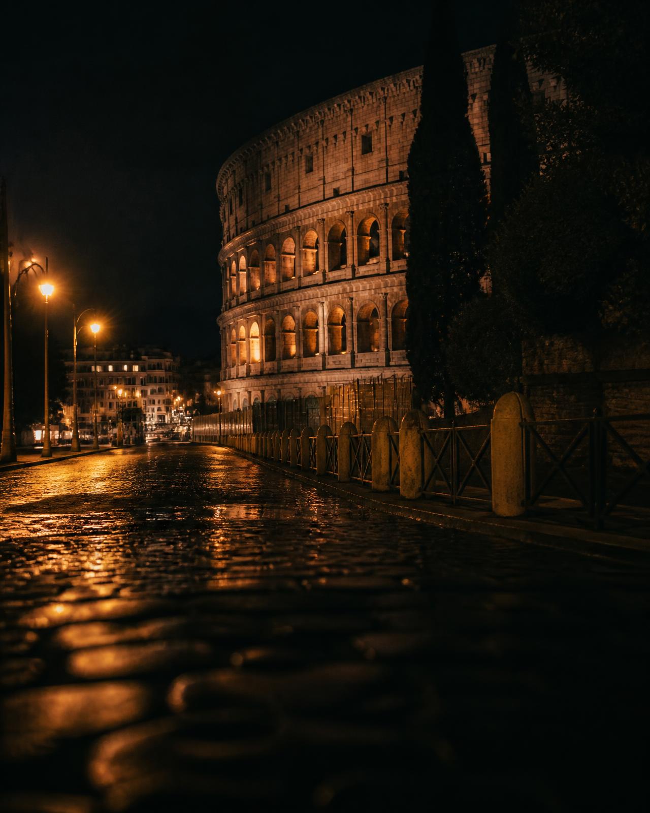 Il Colosseo illuminato di notte con la strada bagnata dalla pioggia